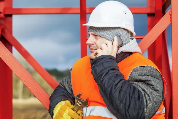 Werknemer met mobiele telefoon in de buurt van metalen constructiewerken — Stockfoto