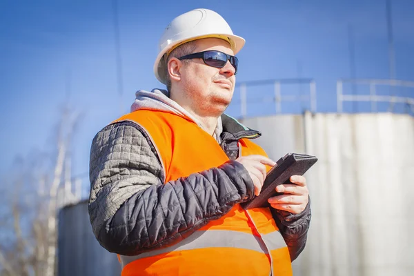 Engineer with tablet PC with oil tank in the background — Stock Photo, Image