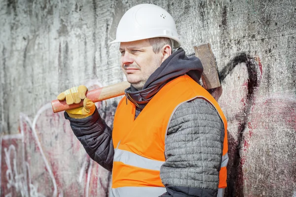 Werknemer met sledge hammer in de buurt van de muur — Stockfoto