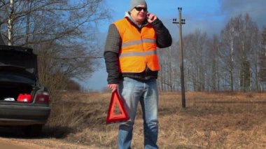 Adam araba yakın cep telefonuyla konuşurken uyarı üçgeni ile