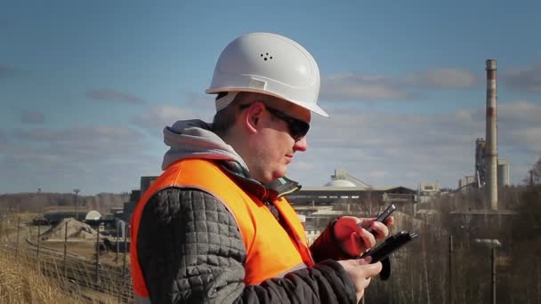 Ingenieur met tablet Pc en mobiele telefoon in de buurt van fabriek — Stockvideo