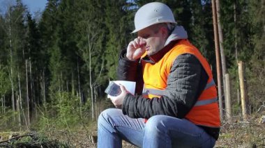 Oduncu ormandaki cep telefonuyla konuşurken para ile