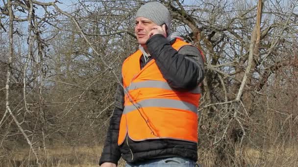 Tuinman praten op mobiele telefoon in de tuin — Stockvideo