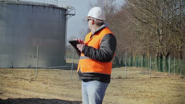Inženýr s počítačem tablet Pc poblíž olejová nádrž — Stock video