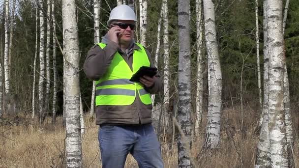 Forest engineer talking on cell phone in birch grove — Stockvideo