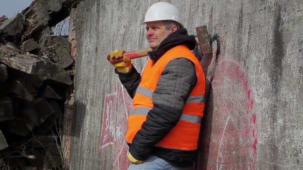 Werknemer met sledge hammer in de buurt van de muur — Stockvideo