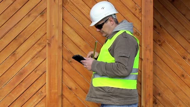 Ingeniero con cinta métrica y tablet PC cerca de edificio de madera — Vídeos de Stock