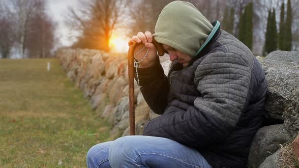 Homme avec chapelet et bâton de marche près des clôtures en pierre — Video