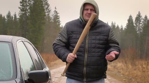 Aggressive man with a baseball bat near car — Stock Video
