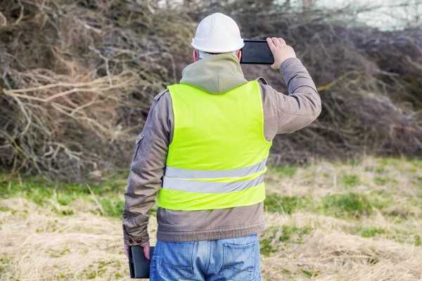 Ingeniero forestal con tableta PC cerca de pila de ramitas — Foto de Stock