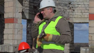 Cep telefonu, mala ve çekiç ile kızgın inşaat işçisi