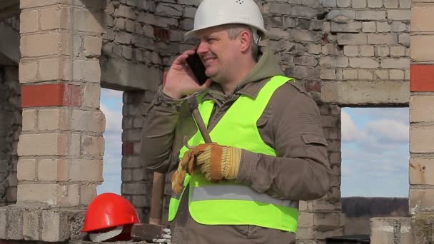 Construction worker with cell phone, trowel and mallet — Stock Video