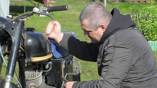 Hombre reparación de la vieja motocicleta al aire libre — Vídeo de stock