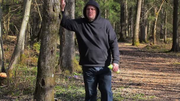 El hombre se calienta en el parque por la mañana cerca del árbol — Vídeo de stock