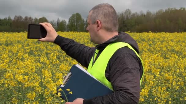 Farmer filmed with tablet PC yellow rape field — Αρχείο Βίντεο