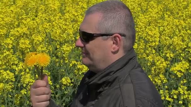 Men with dandelions near rape field — Stock Video