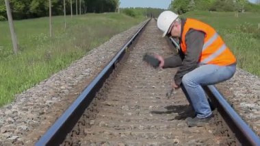 Demiryolunda cep telefonuyla konuşan bir işçi.