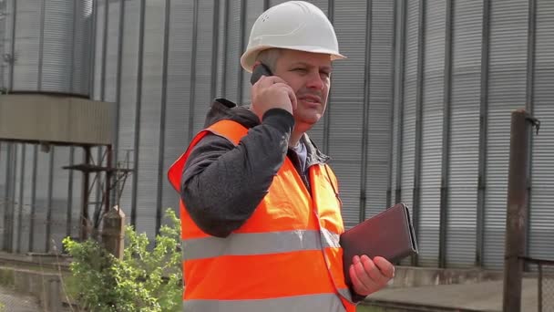 Engineer talking on cell phone at the factory — Stock Video