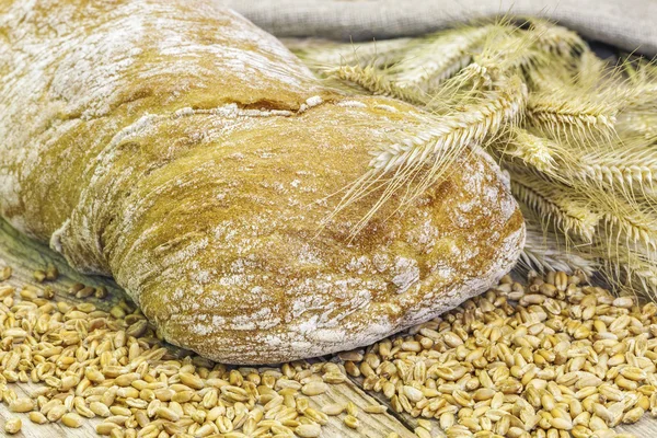 Pão com grãos e orelhas na mesa — Fotografia de Stock