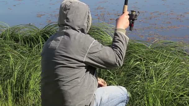 Hombre con caña de pescar en el lago en verano — Vídeo de stock