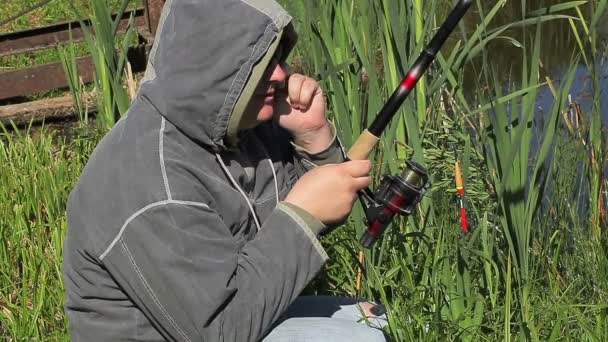 Man met hengel en mobiele telefoon aan het meer — Stockvideo