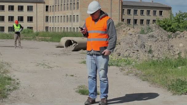 Empregados de construção com telefone celular e documentos — Vídeo de Stock