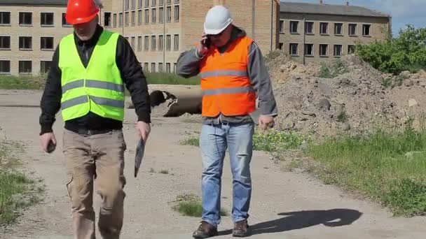 Pracowników budowlanych rozmowy w pobliżu niedokończony budynek — Wideo stockowe