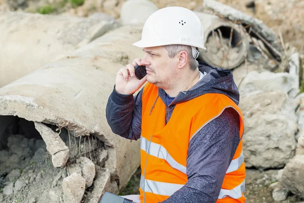 Ingenieur met mobiele telefoon op de gebroken beton pijp — Stockfoto