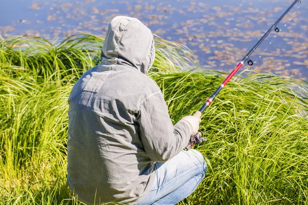 Uomo pesca vicino lago in estate — Foto Stock