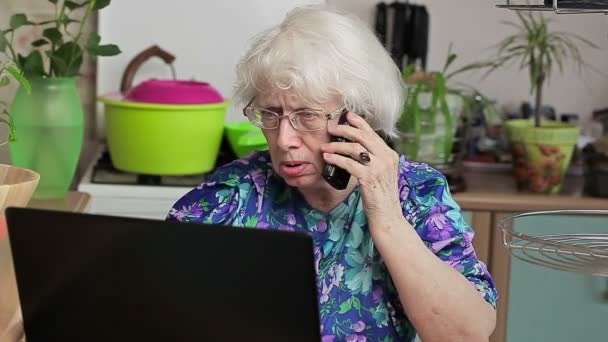 Señora mayor con teléfono celular cerca de la computadora portátil — Vídeo de stock