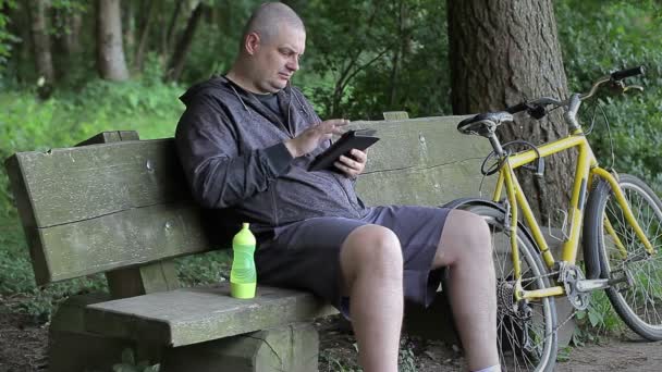 Человек с планшетным ПК рядом с велосипедом — стоковое видео