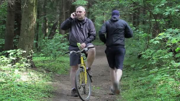 Man op fiets met mobiele telefoon in het park — Stockvideo