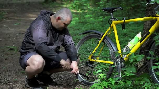Homem com bomba perto de pneu de bicicleta na floresta — Vídeo de Stock