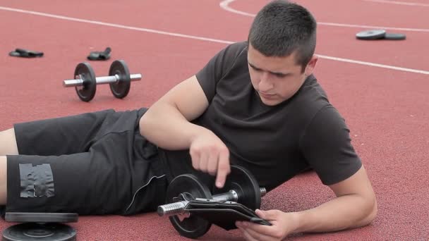 Adolescent en utilisant la tablette PC près des haltères — Video