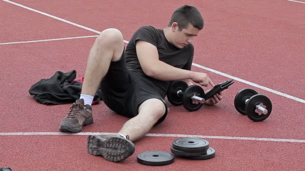 Підліток використовує планшетний ПК на спортивному майданчику — стокове відео