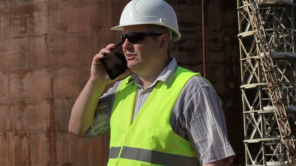 Ingenieur smartphone bij gebruik buiten in de buurt van tank — Stockvideo