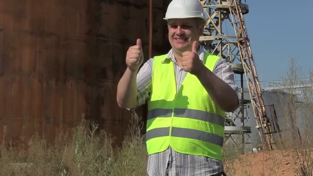 Ingeniero feliz mostrando pulgares cerca de los tanques — Vídeos de Stock