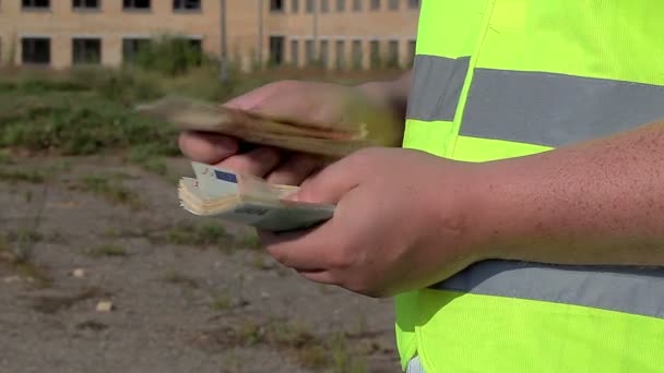 Construction worker to count money near building — Stock Video