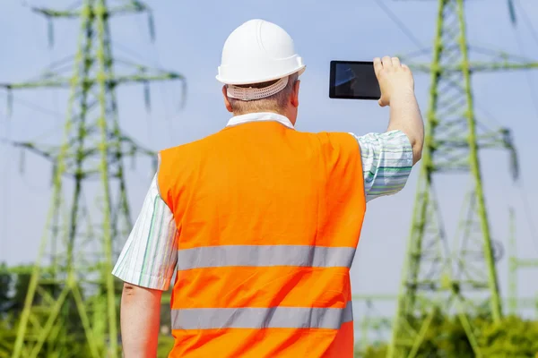 Electrical engineer filmed with tablet PC near high voltage power line — Stock Photo, Image