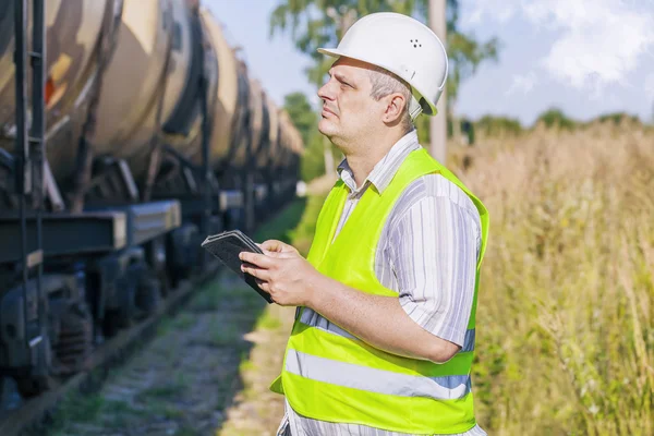 Spoorweg ingenieur met behulp van tablet Pc op spoorlijn in de buurt van goederenwagons — Stockfoto