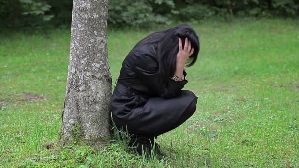 Femme déprimée assise près de l'arbre dans le parc — Video