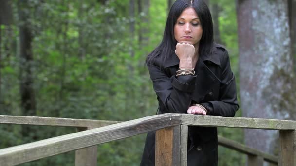 Depressieve vrouw op de brug in het park — Stockvideo