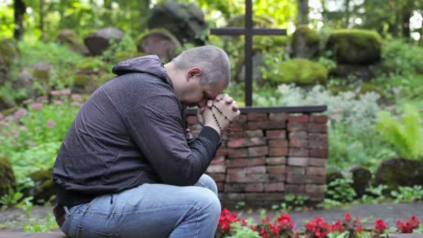 Man be på bänk med Rosenkransen på utomhus kyrka — Stockvideo