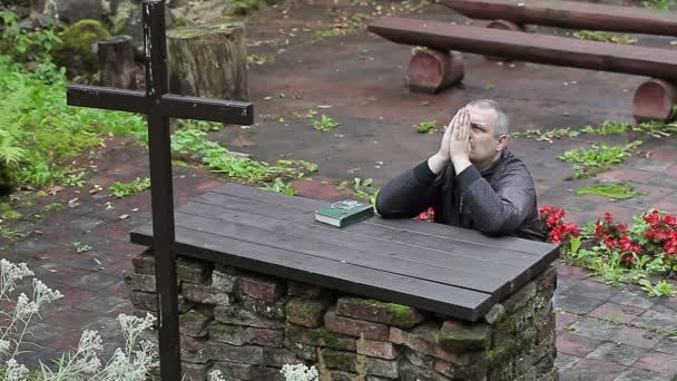 El hombre con Biblia y rosario reza arrodillado ante el altar — Vídeo de stock