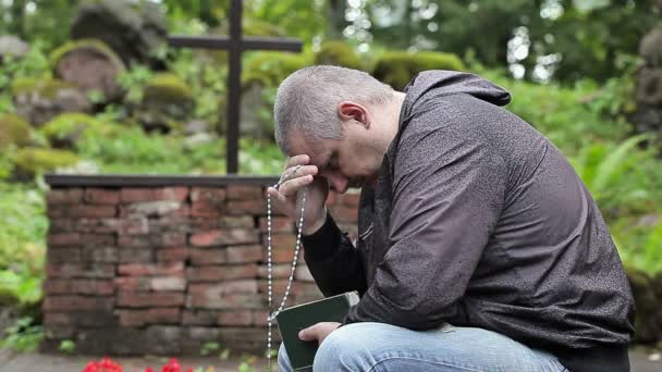 Ember a Biblia és a rózsafüzér imádkozás a szabadban templom közelében kereszt — Stock videók