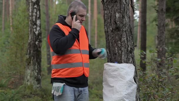 Uomo con cellulare e sacchetto di bottiglie di plastica nella foresta — Video Stock