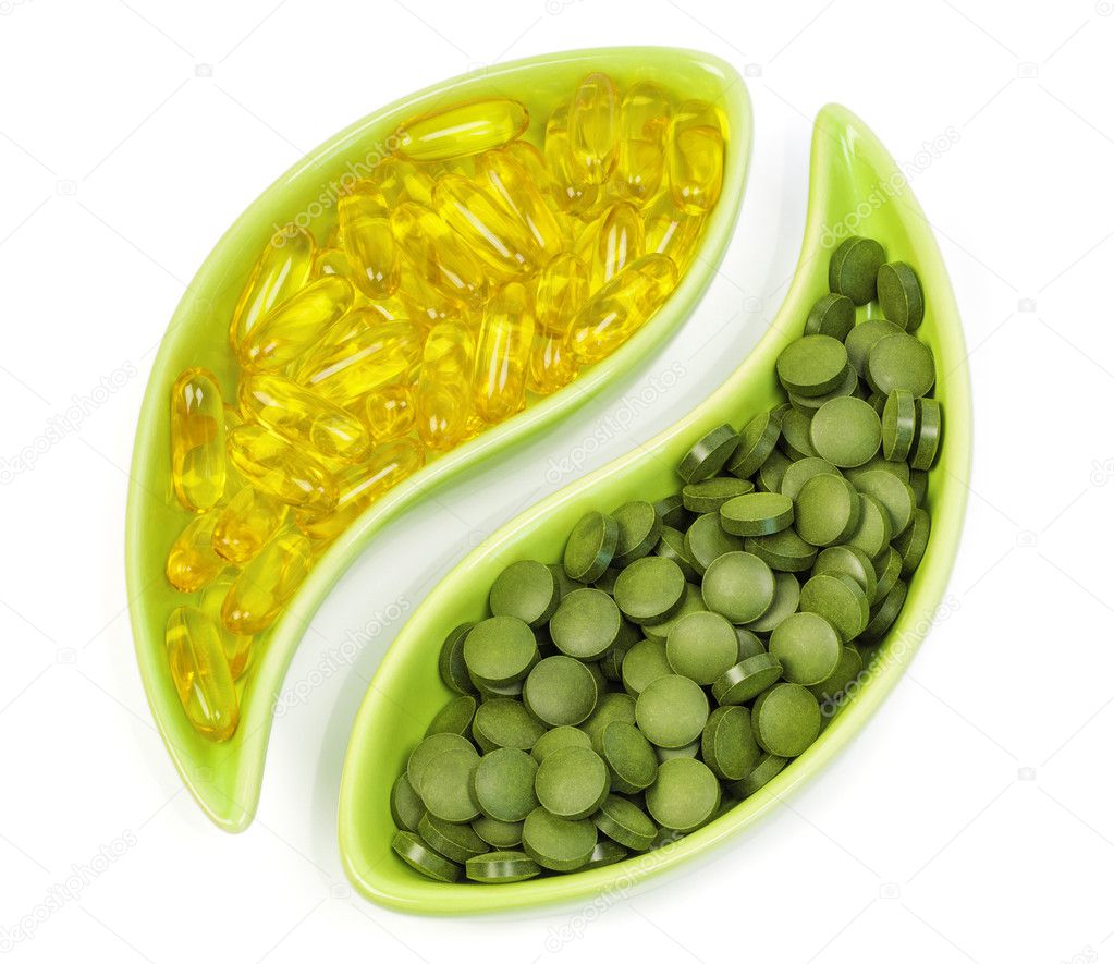 Fish oil capsules and organic spirulina tablets in bowls
