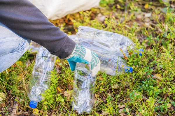 Человек с мешком собирает использованные пластиковые бутылки — стоковое фото