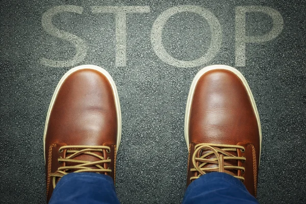 Man before warning message stop on asphalt — Stock Photo, Image