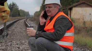 Kahve içme ve smartphone üzerinde konuşurken demiryolu çalışanı